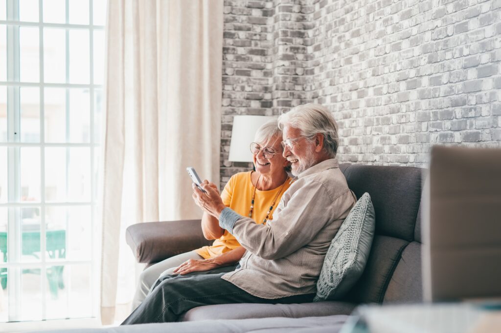 Elderly grandfather and grandmother spend time having fun using smartphone apps